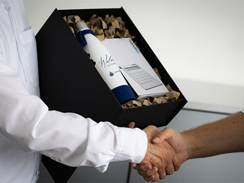 REFLECTS gift set as onboarding box for new employees Shaking hands with an open onboarding box