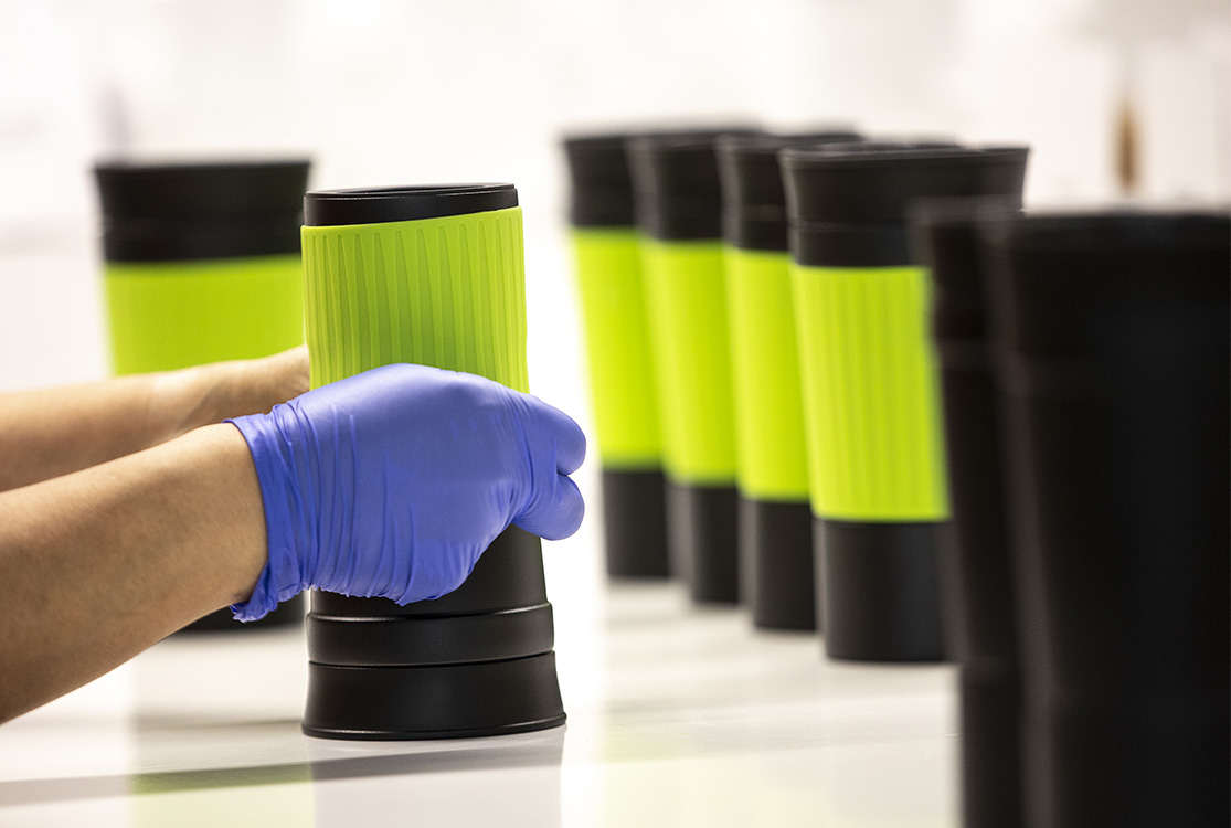 Final assembly of promotional items in Cologne Silicone sleeve is pulled over thermo cup by hand