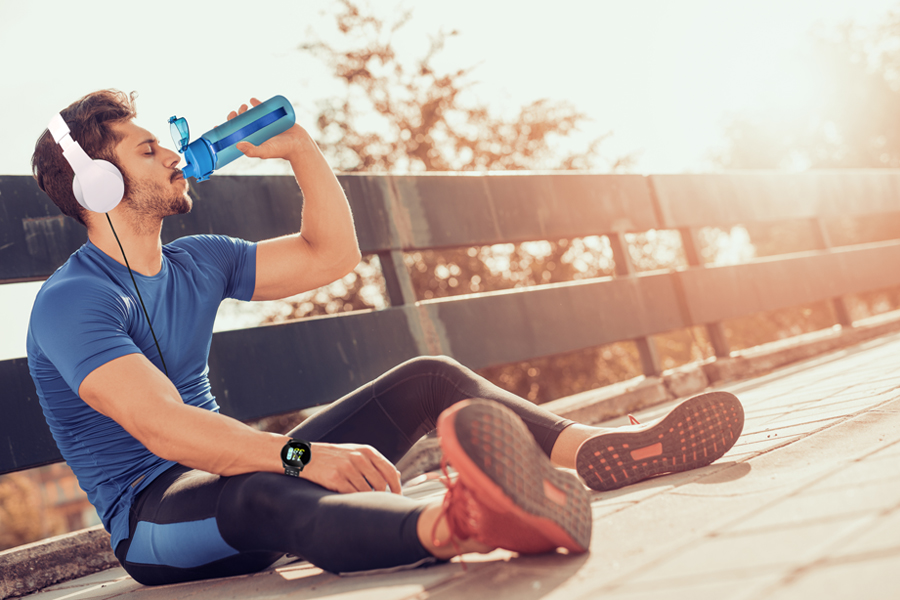 Sporttrinkflasche als Werbeartikel Mann macht Pause beim Sport mit Kopfhörer und Trinkflasche