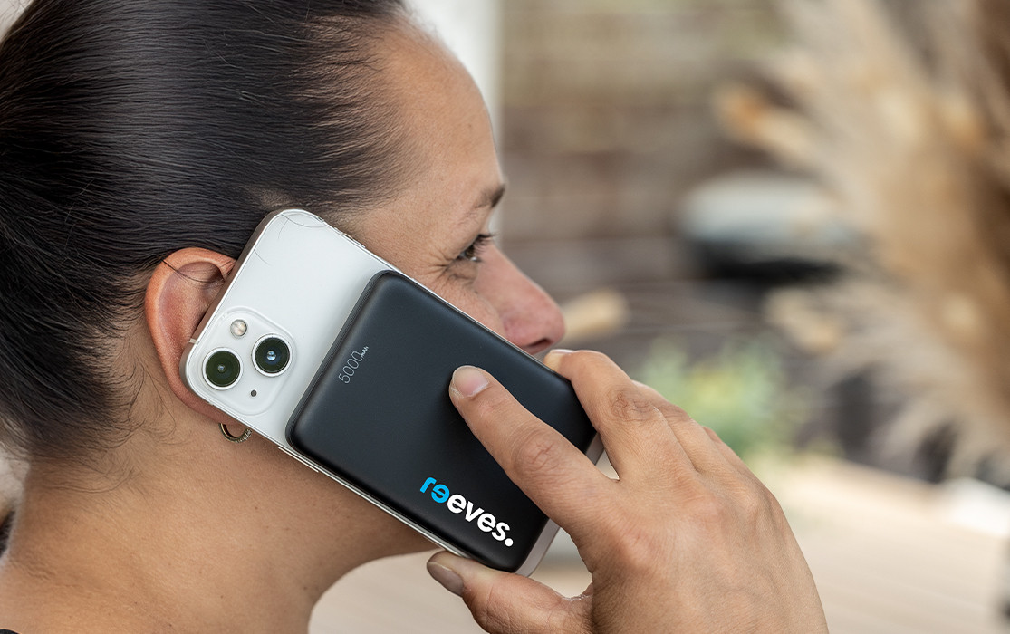 Nouveauté publicitaire - Powerbank 5.000 mAh avec MagSafe® - REEVES-BOSTROCK Femme au téléphone avec powerbank magnétique au dos du smartphone