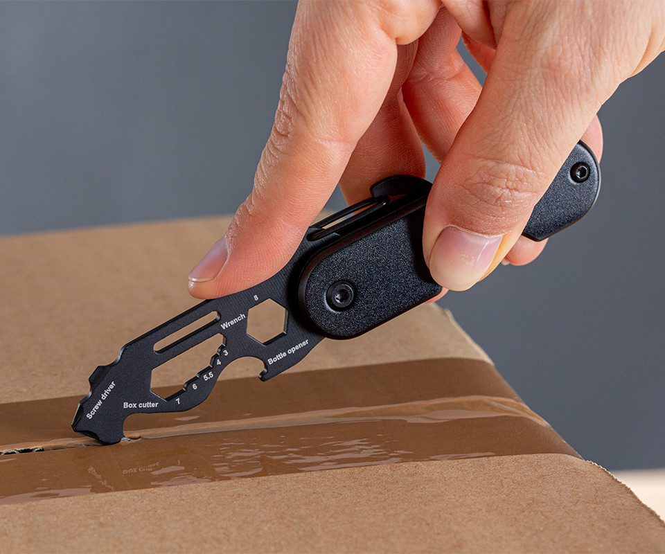 Multitool avec ouvre-paquet comme article publicitaire Découpe d'un carton d'expédition avec coupe-paquet sur Multitool