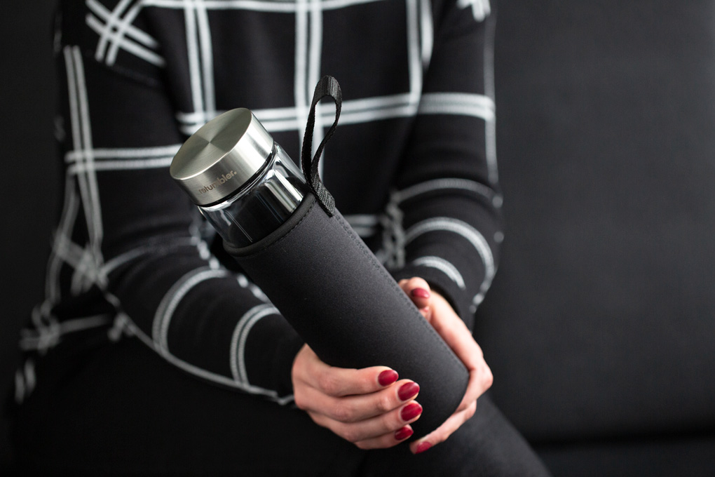 Trinkflasche aus Glas als Werbeartikel Zylindrische Glastrinkflasche in Neopren Sleeve in Frauenhand