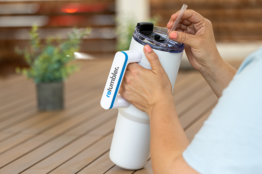 XXL Termobecher mit Henkel in Benutzung XXL Thermobecher in weiblichen Händen an Terrassentisch